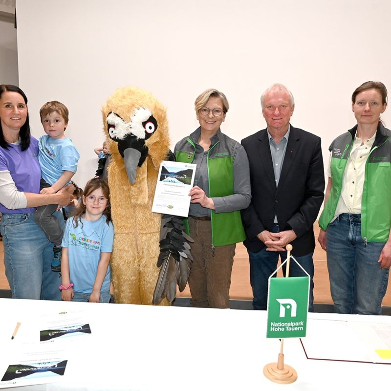 Kindergartenleiterin Melanie Striednig-Bär, die Kindergartenkinder, „Bärbl Bartgeier“, Nationalparkdirektorin Barbara Pucker, Bürgermeister Günther Novak und Projektleiterin Monika Auinger bei der feierlichen Unterzeichnung der Verlängerung der Kindergartenkooperation.